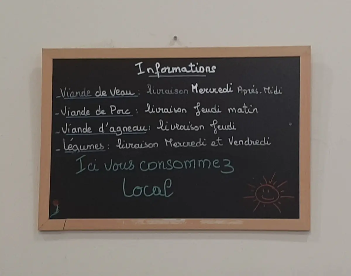 L&rsquo;ardoise du magasin, avec les jours de livraison et la mention « Ici vous consommez local »