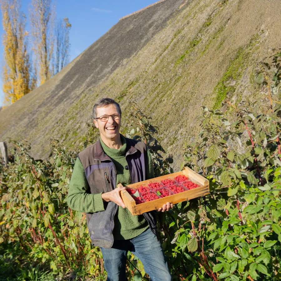 Marc dans ses vergers à Charavines, une cagette de fruits à la main